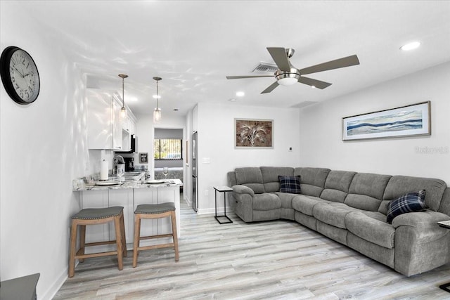 living room featuring ceiling fan, sink, and light wood-type flooring