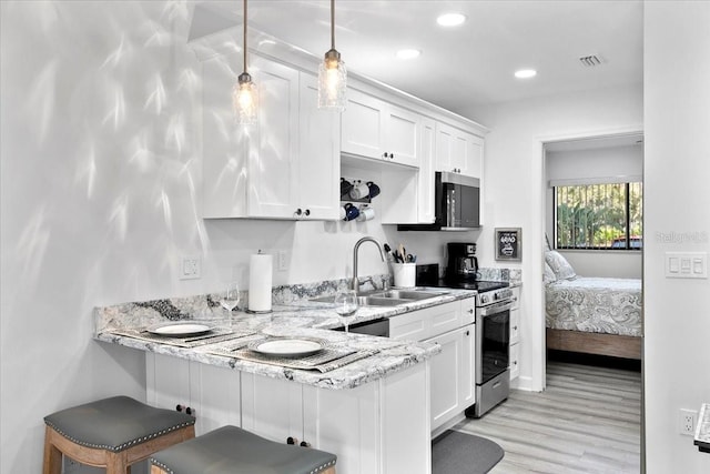 kitchen featuring hanging light fixtures, a kitchen breakfast bar, white cabinets, and appliances with stainless steel finishes