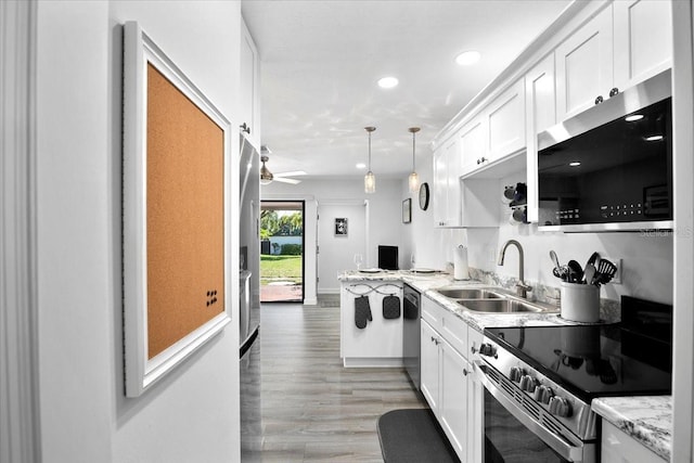 kitchen featuring sink, white cabinetry, decorative light fixtures, stainless steel appliances, and light stone countertops