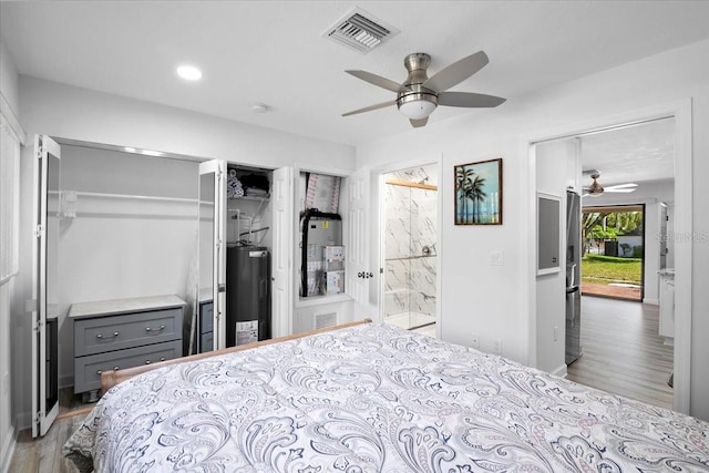 bedroom with ceiling fan, ensuite bathroom, light hardwood / wood-style floors, and electric water heater