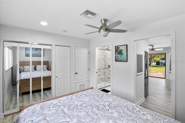 bedroom featuring two closets, hardwood / wood-style flooring, ceiling fan, and ensuite bathroom