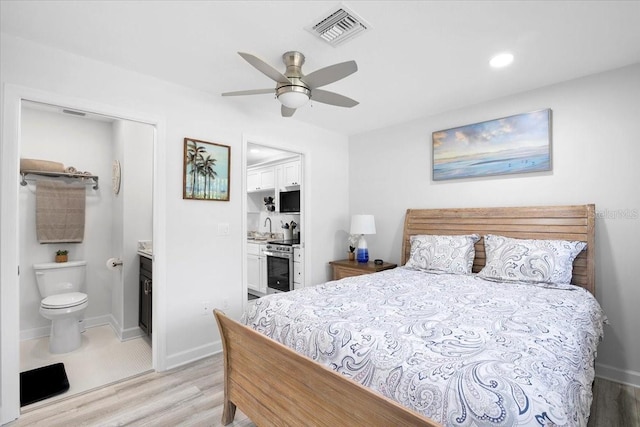 bedroom with sink, light wood-type flooring, ceiling fan, and ensuite bathroom