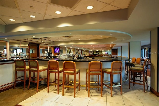 bar featuring light tile patterned floors and a drop ceiling