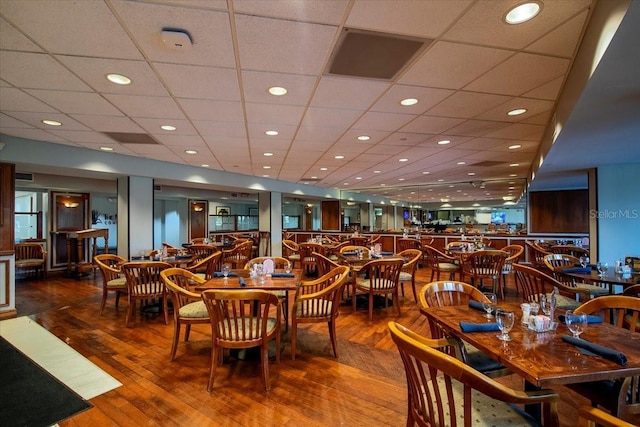 dining space with wood-type flooring and a drop ceiling