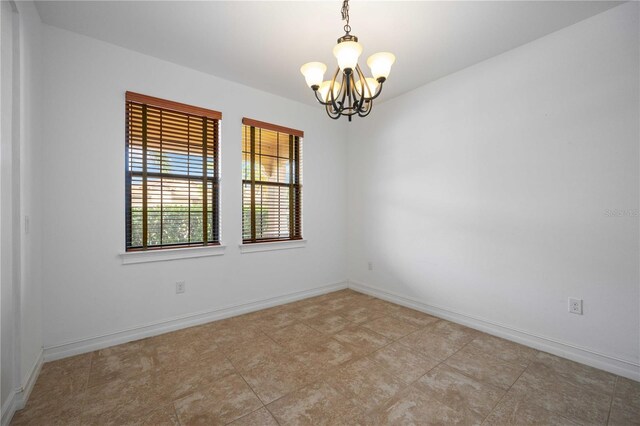 tiled empty room featuring a chandelier