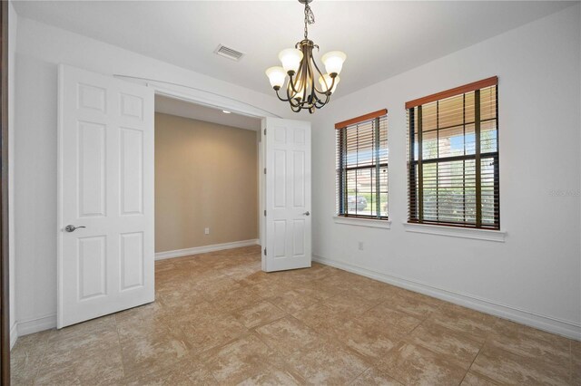 tiled empty room featuring a chandelier