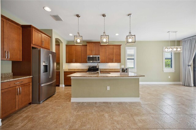 kitchen with decorative backsplash, appliances with stainless steel finishes, a kitchen island with sink, and light tile patterned floors