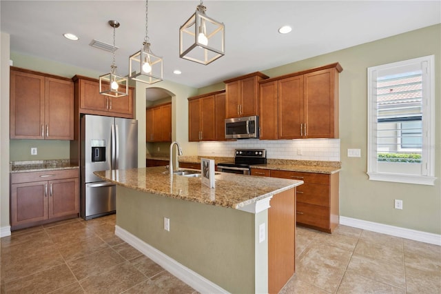 kitchen featuring light tile patterned floors, a kitchen island with sink, stainless steel appliances, and tasteful backsplash