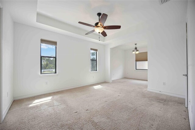 unfurnished room featuring ceiling fan, light colored carpet, and a tray ceiling