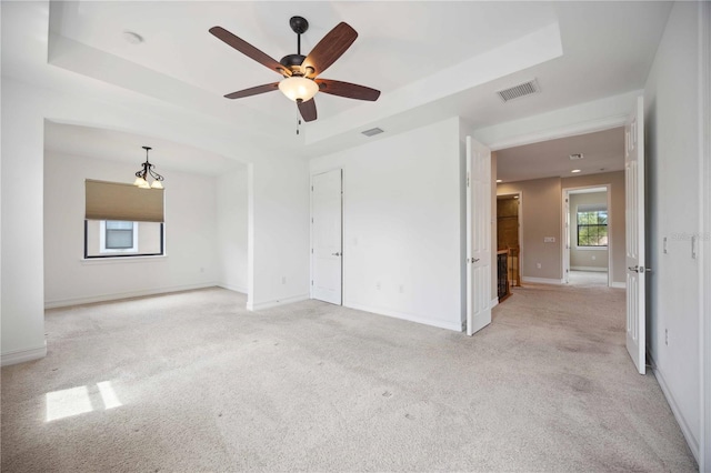 carpeted spare room with ceiling fan and a tray ceiling