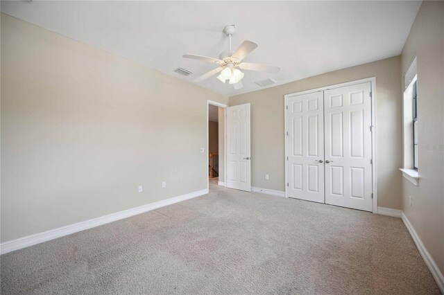 unfurnished bedroom with light colored carpet, a closet, and ceiling fan