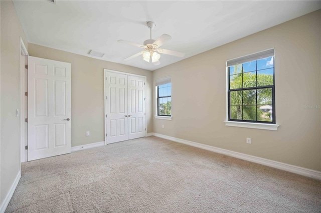 unfurnished bedroom with light carpet, a closet, ceiling fan, and multiple windows