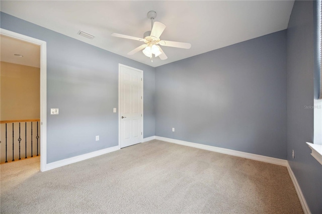 empty room featuring ceiling fan and light colored carpet