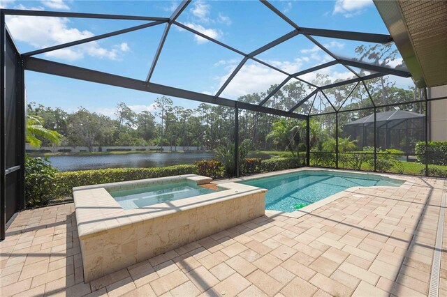 view of swimming pool with glass enclosure, a water view, an in ground hot tub, and a patio area