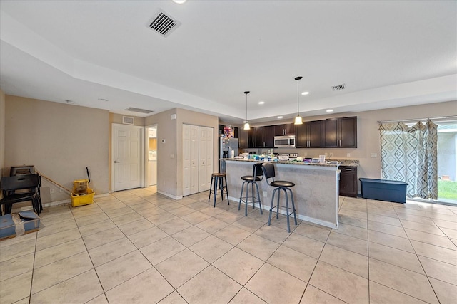 kitchen featuring a kitchen breakfast bar, a center island, dark brown cabinets, light tile patterned floors, and pendant lighting