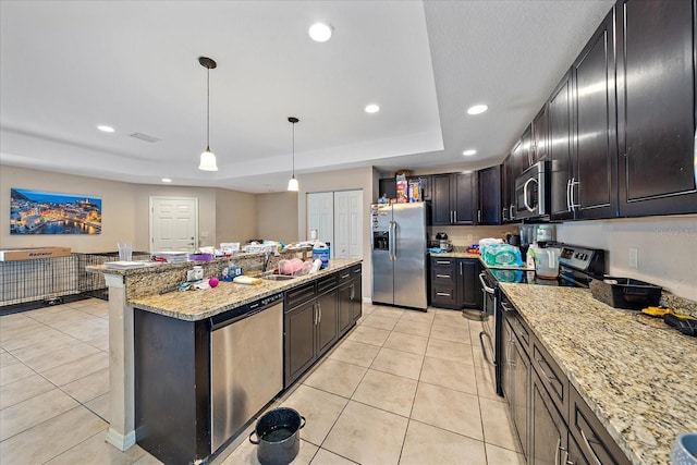 kitchen featuring appliances with stainless steel finishes, light stone counters, pendant lighting, light tile patterned floors, and a center island