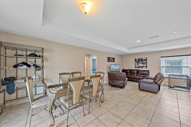 dining space featuring light tile patterned floors and a tray ceiling