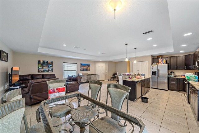 dining room with a raised ceiling and light tile patterned floors