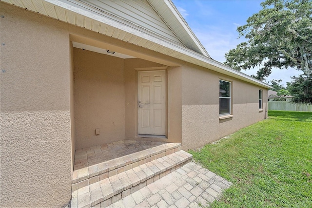 view of exterior entry featuring a yard