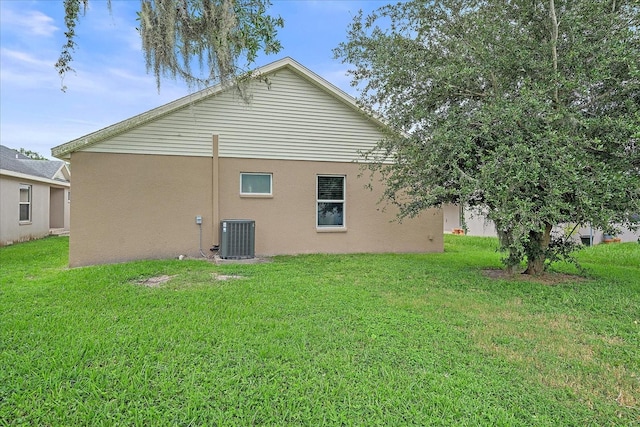 back of property with central AC unit and a lawn