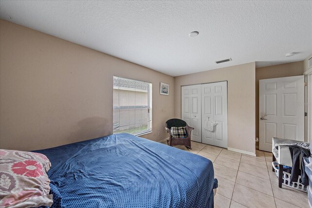 tiled bedroom with a closet and a textured ceiling