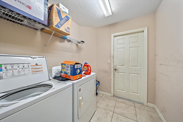 laundry room featuring light tile patterned floors, washing machine and clothes dryer, and a textured ceiling