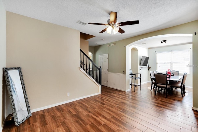 living room with ceiling fan, wood-type flooring, and a textured ceiling