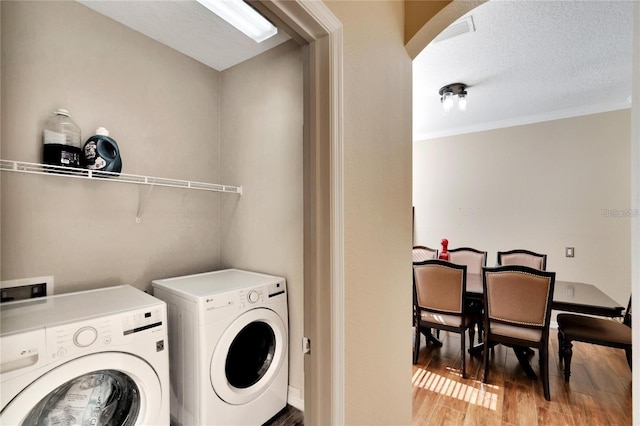 washroom with light hardwood / wood-style flooring, a textured ceiling, washer and dryer, and crown molding