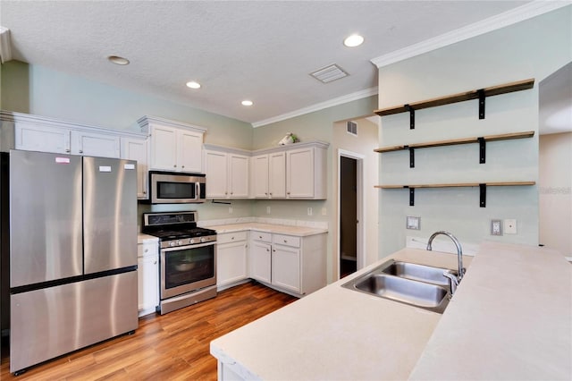 kitchen with white cabinets, stainless steel appliances, sink, and light hardwood / wood-style floors