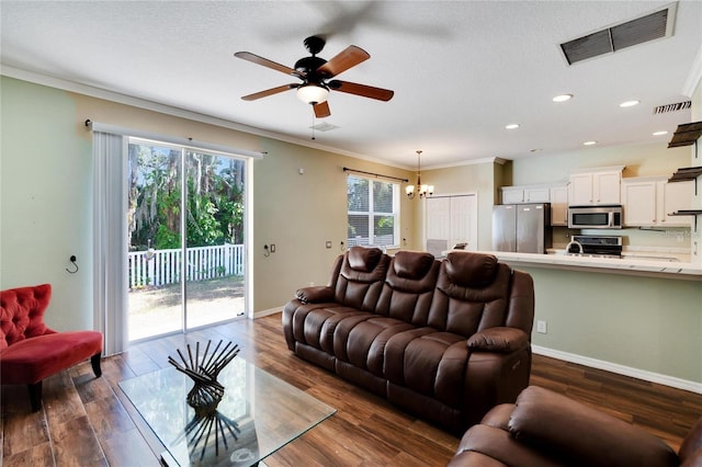 living room with ceiling fan with notable chandelier, dark hardwood / wood-style flooring, and crown molding