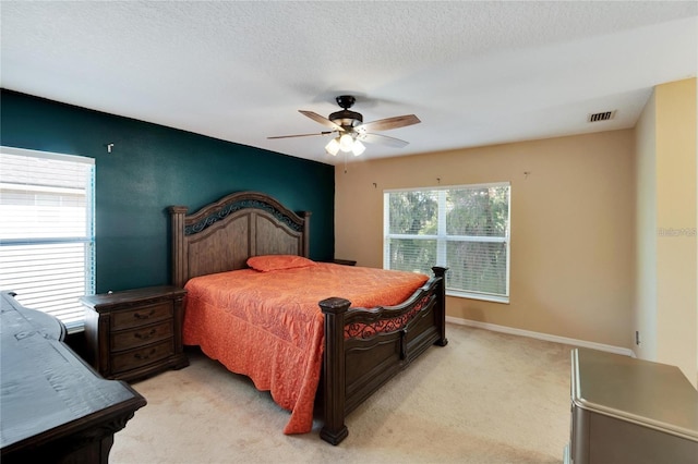 bedroom with ceiling fan, a textured ceiling, and light colored carpet