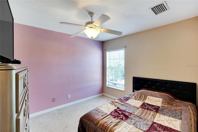 bedroom featuring ceiling fan, a textured ceiling, and light carpet