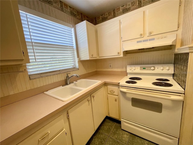 kitchen featuring sink, electric stove, dark tile patterned flooring, and white cabinetry