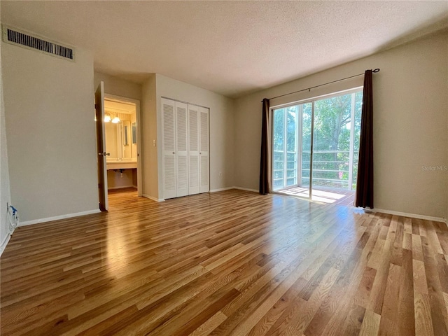 unfurnished bedroom featuring a textured ceiling, access to exterior, a closet, and wood-type flooring