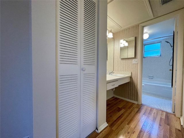 bathroom with wood-type flooring, crown molding, vanity, and tiled shower / bath