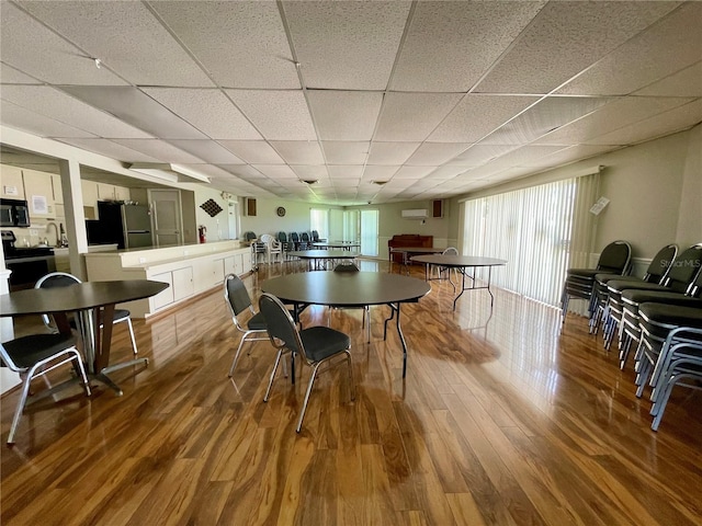 dining area with a drop ceiling and wood-type flooring