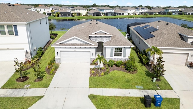 view of front of house featuring driveway, stone siding, a residential view, and a water view