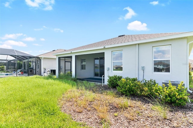 back of house with stucco siding, glass enclosure, and central air condition unit