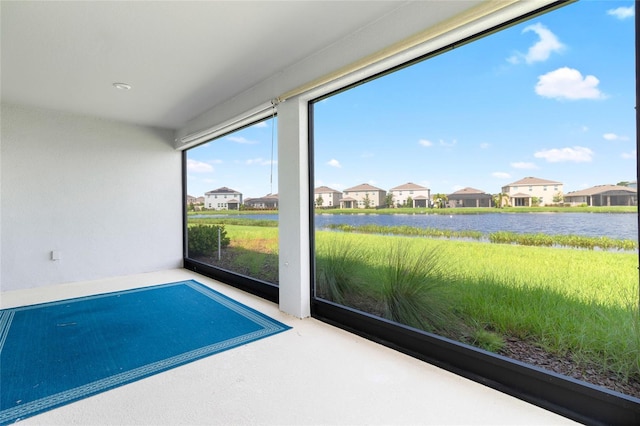 unfurnished sunroom featuring a water view and a residential view