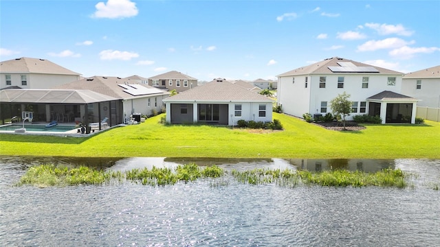 rear view of property with a residential view, glass enclosure, a water view, and a yard