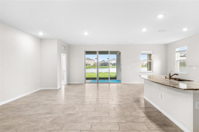 unfurnished living room with a wealth of natural light, baseboards, and recessed lighting