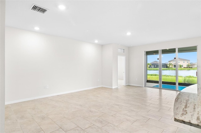 empty room with a water view, baseboards, visible vents, and recessed lighting