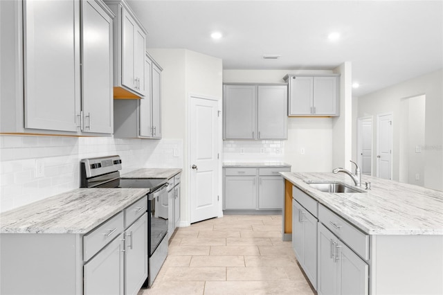 kitchen featuring stainless steel range with electric stovetop, gray cabinets, a sink, and decorative backsplash