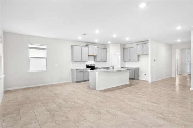 kitchen with light stone counters, recessed lighting, electric range, gray cabinetry, and a kitchen island with sink