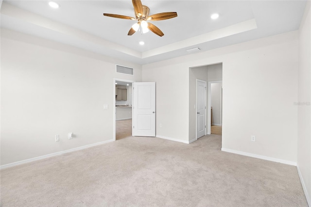 unfurnished bedroom with recessed lighting, a raised ceiling, light colored carpet, visible vents, and baseboards