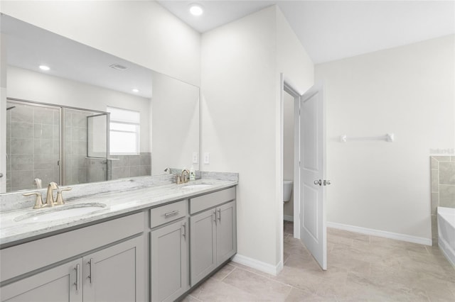 bathroom with a stall shower, a sink, toilet, and double vanity