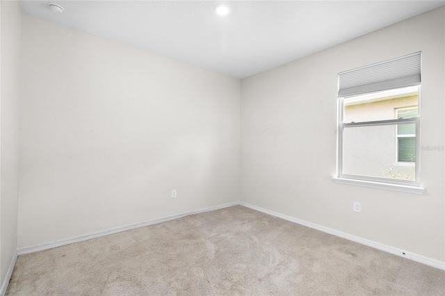 unfurnished room with light carpet and baseboards