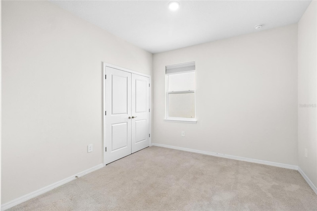 unfurnished room featuring light colored carpet and baseboards