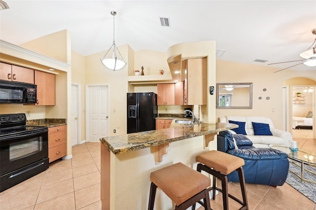 kitchen with black appliances, sink, light tile patterned flooring, and a breakfast bar