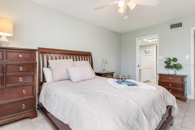 tiled bedroom with a textured ceiling, ceiling fan, and ensuite bathroom